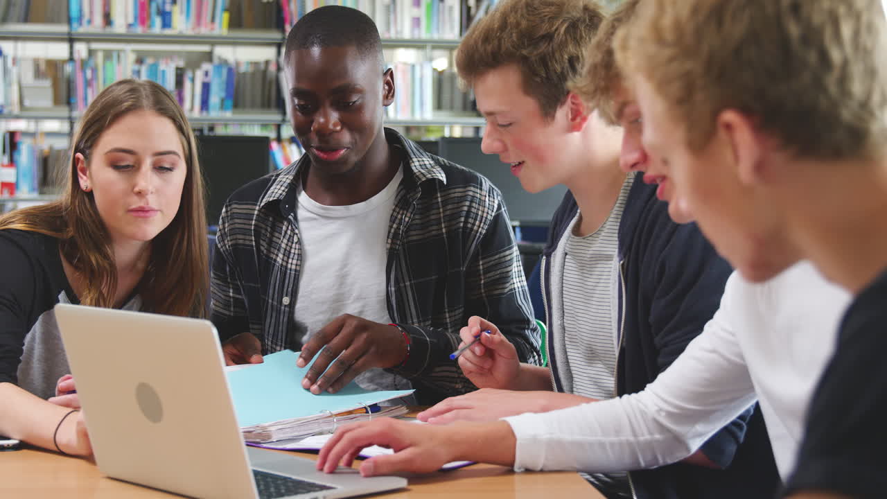 grupo de estudiantes universitarios trabajando en la biblioteca con una computadora portátil