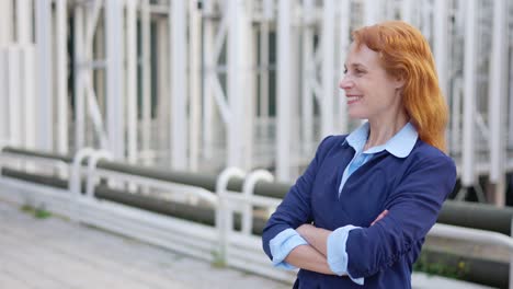 smiling businesswoman with red hair posing outdoors