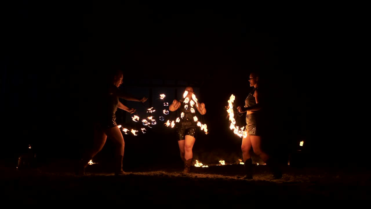 группа жонглировщиков огнем. люди плюют огонь в темную ночь на открытом воздухе.