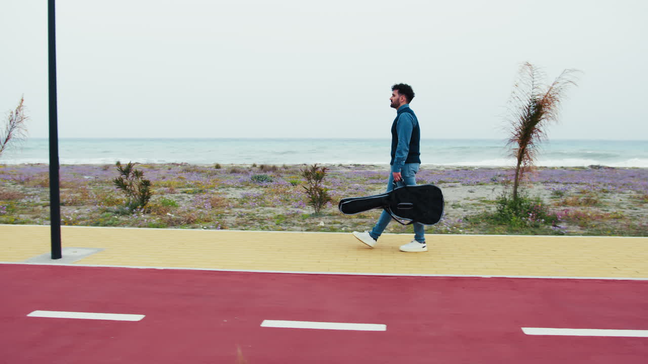 Man Walking with a Guitar Case along a Coastal Path