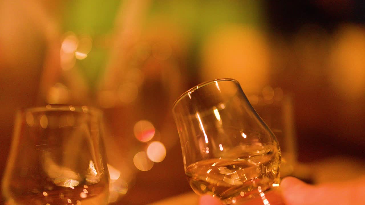 Close-up of hand swirling whisky glass, warm lighting, shallow depth, smooth camera movement