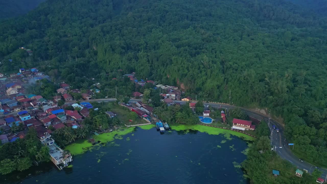 A rising pull-out aerial of dense tropical forest and winding hillside road in Talisay, Batangas, Philippines