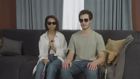 front view of blind friends sitting on a sofa in a flat