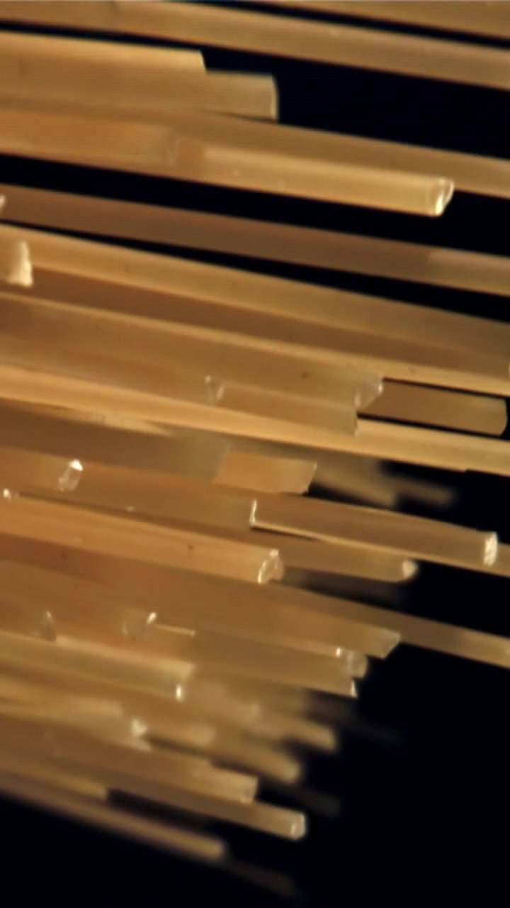 Primo piano di spaghetti secchi che cadono su sfondo nero