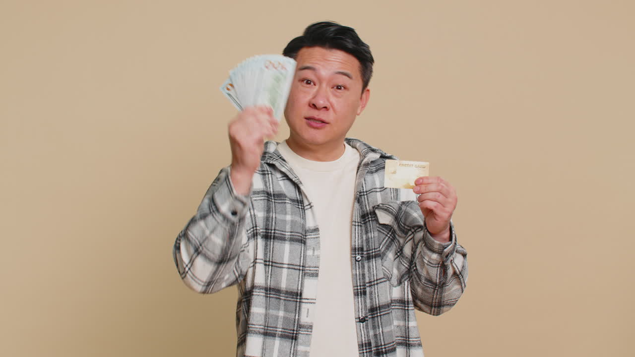 Happy asian man showing plastic credit bank card and money dollar cash advertising taking loan