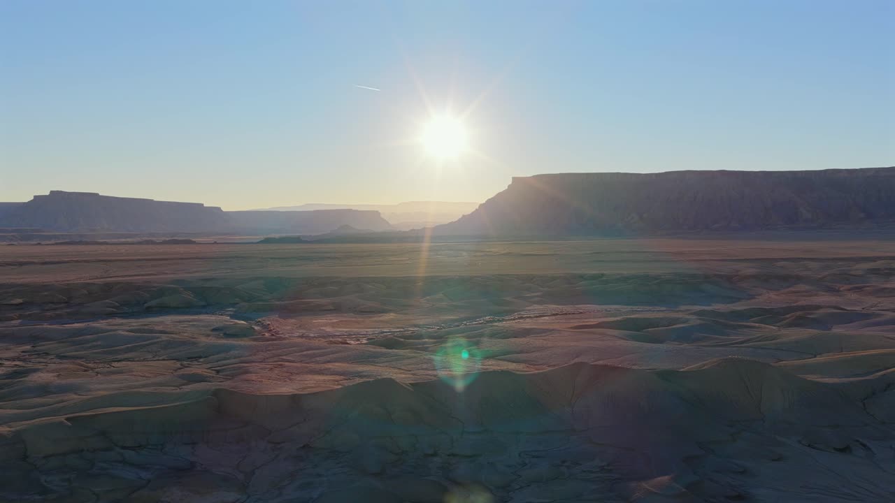 Un'ampia prospettiva aerea da drone rivela i calanchi fortemente erosi e i profondi canyon vicino a Hanksville, Utah. Questo paesaggio misterioso e fantascientifico è caratterizzato da un terreno alieno e un vasto orizzonte desertico al tramonto.