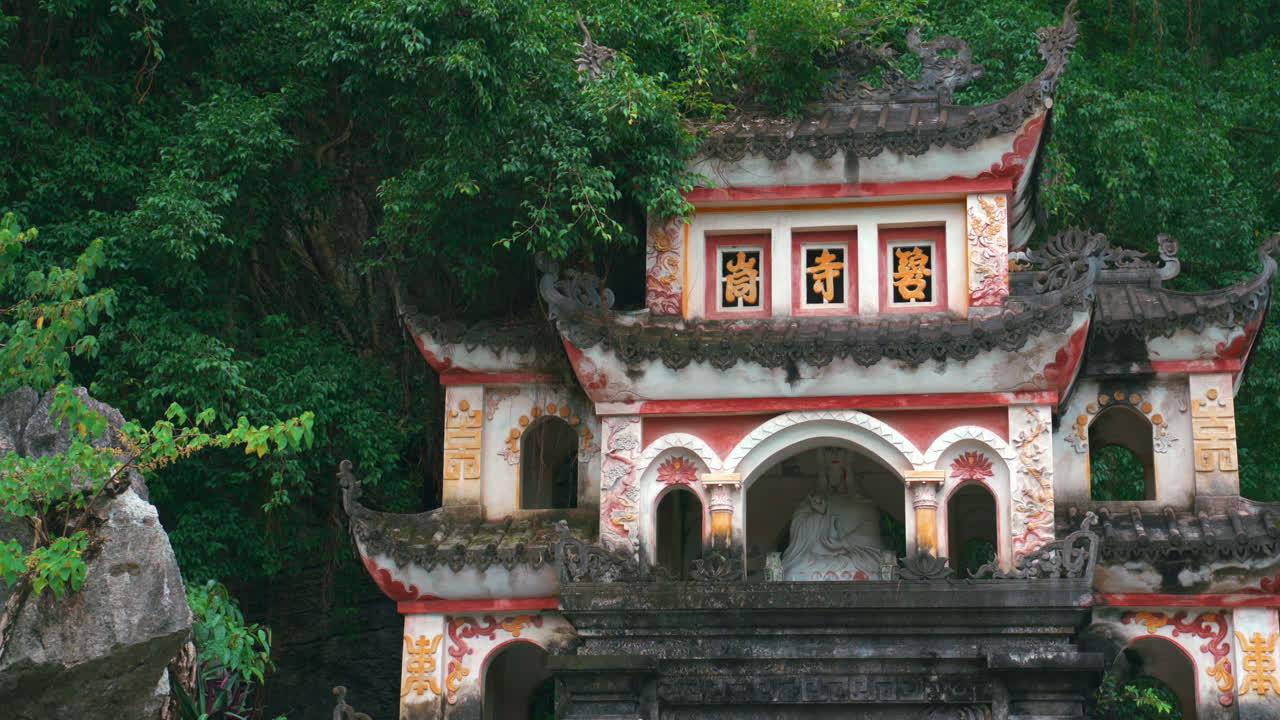 Nærbillede af den udsmykkede facade på Bich Dong-pagoden, der viser traditionelle relieffer og buddhistiske statuer integreret i bjerget i Ninh Binh, Vietnam