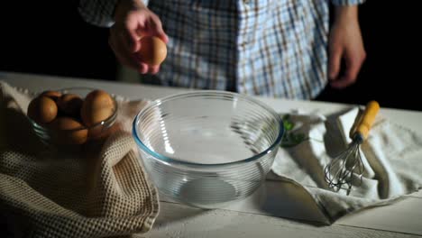 man hand breaks chicken egg in bowl. chef cracked egg in glass bowl