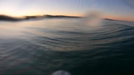 surfer paddling and surfing a reef wave in ambient morning light on tropical surf spot