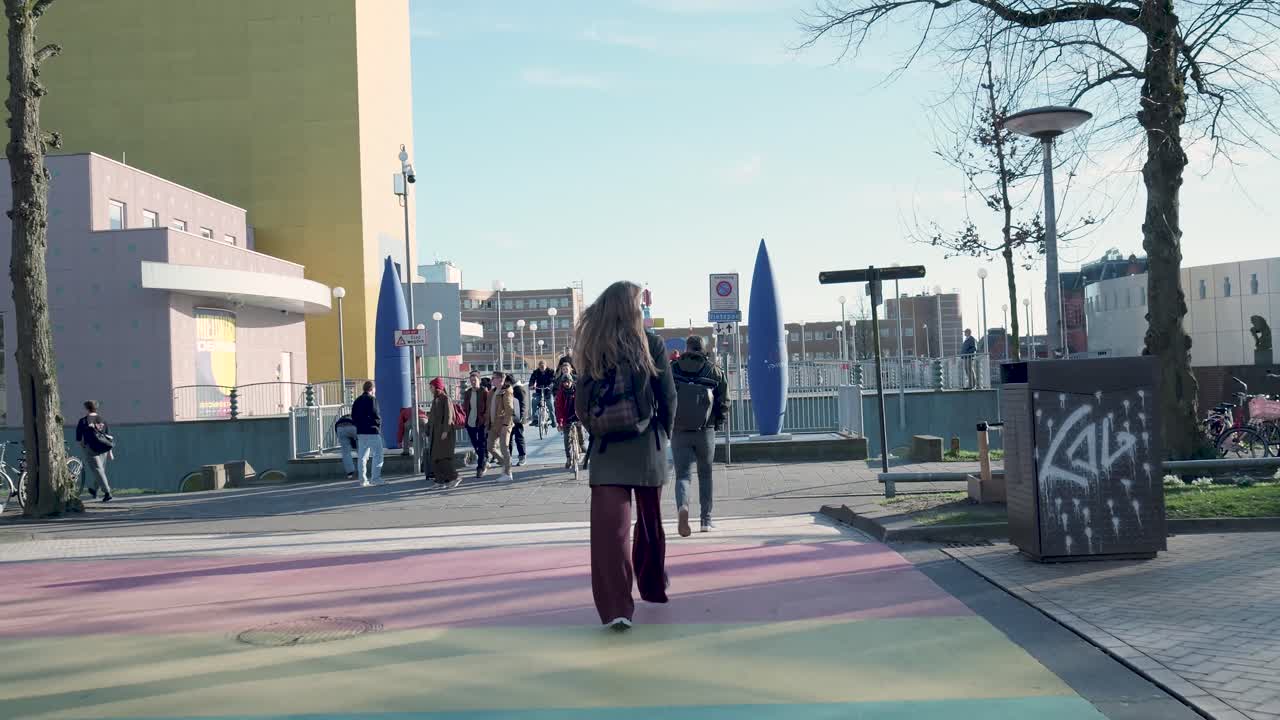 Jeune femme marchant sur une allée piétonne colorée en ville