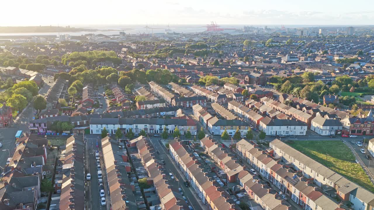 Cinematic aerial drone footage of the neighborhood surrounding Liverpool FC’s iconic Anfield stadium, captured during sunset. The golden-hour light highlights residential streets, rows of houses