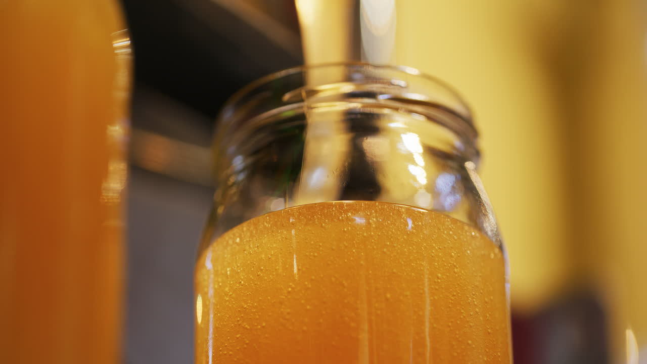 Pouring Fresh Natural Rapeseed Honey into Jar