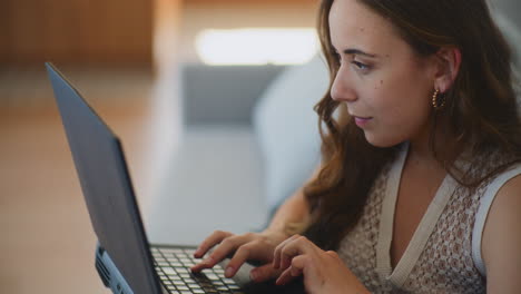 mujer escribiendo en el sofá de la computadora portátil