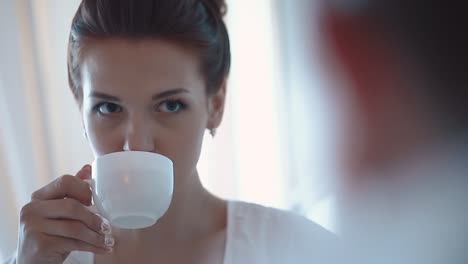 una chica linda mira al joven y bebe café de cerca