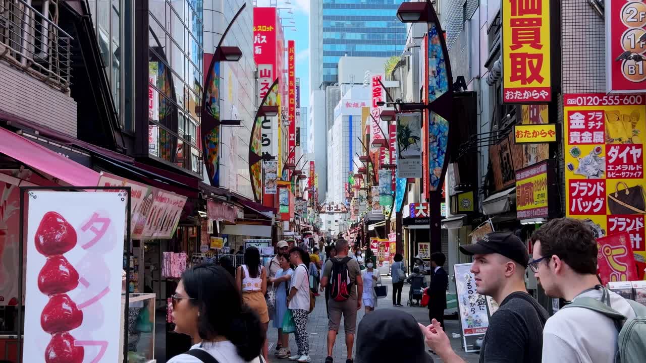 Bustling city street with tall buildings and bright signs on a clear day in Japan