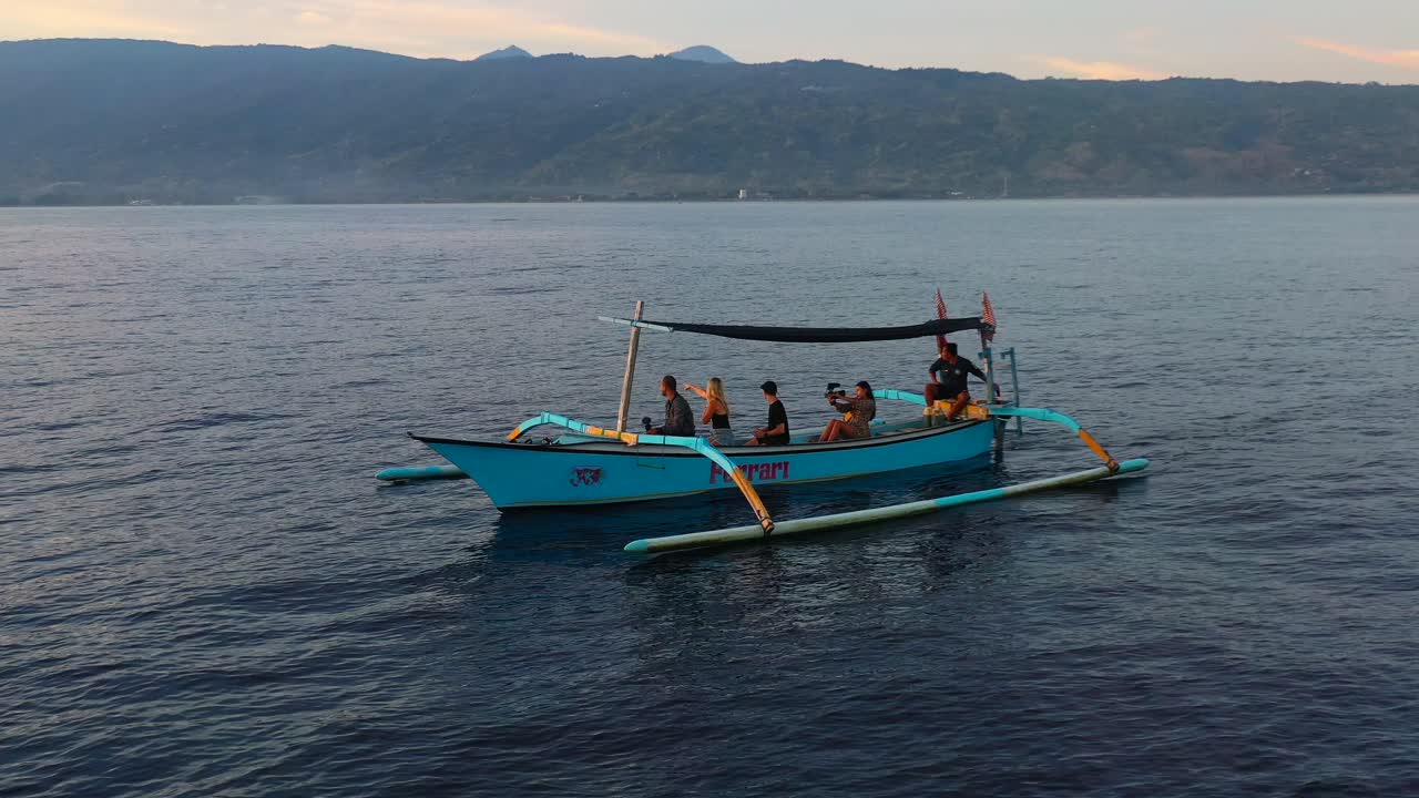 aerial of tourists searching for dolphins on clam flat ocean in Lovina Bali Indonesia during sunrise