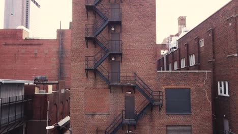 fire escape ladder and stairs on the outside of a brick building downtown in the city