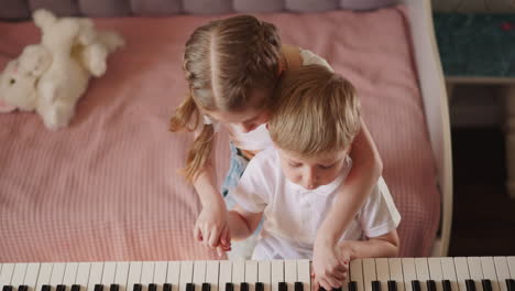 Girl-with-braided-hair-plays-melody-on-piano-with-brother