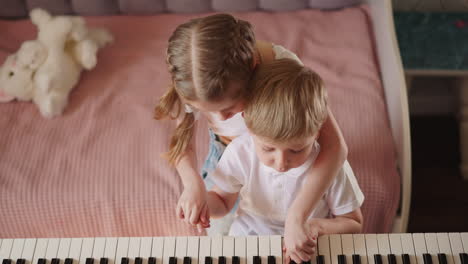 girl with braided hair plays melody on piano with brother