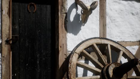 vieja rueda de madera y puerta negra en la casa blanca