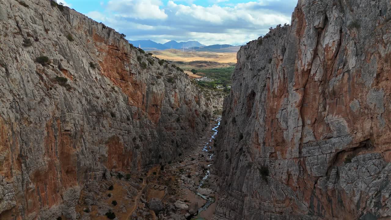 Volo di drone a bassa quota che traccia il bordo di una scogliera spettacolare e di una valle rocciosa in una provincia. La telecamera si inclina verso l'alto per rivelare un'estensione infinita degli altipiani interni spagnoli sotto un cielo blu profondo.