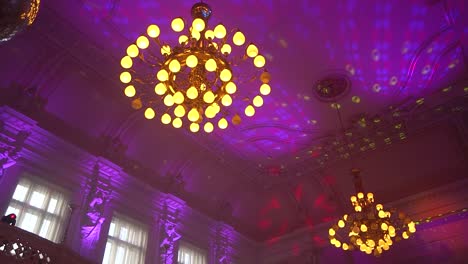 ceiling of a baroque hall with golden decorative chandeliers and party lights