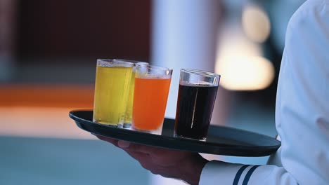 a waiter holds a tray of different soft drinks in glasses during an event