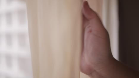 selective focusing view of hand's man while closing the curtain for big window in hotel room in morning