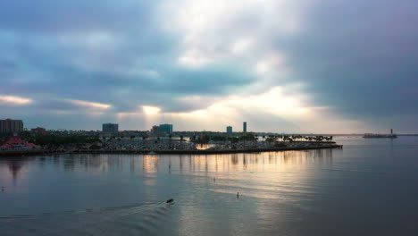 Fishermen-in-a-small-motorboat-heading-out-to-sea-from-the-harbor-in-Long-Beach,-California-at-sunrise---aerial-view