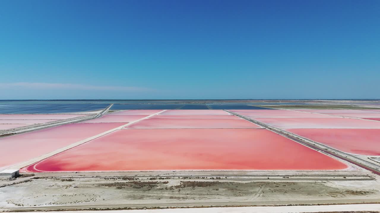 알바니아의 바다 소금 농장 위를 날아다니며 분홍색 퇴적물, 파란 하늘 바가