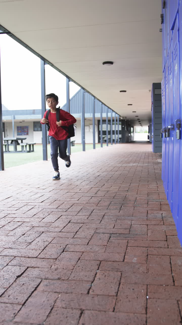 Vertical video: In a school corridor, a young Asian student walks alone