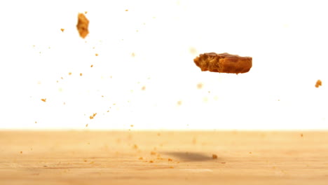 una galleta cayendo y rompiéndose en una mesa de madera