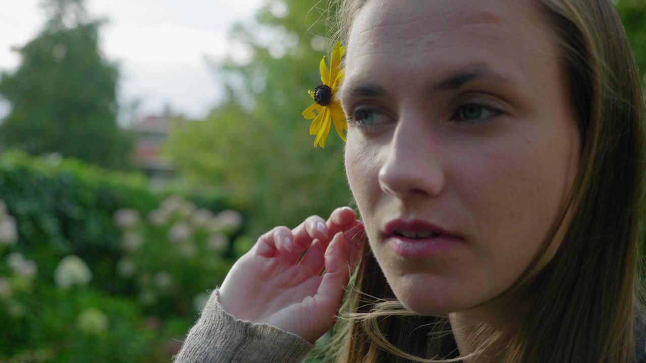 chica coloca flor de margarita dorada en el cabello, primer plano, cámara lenta