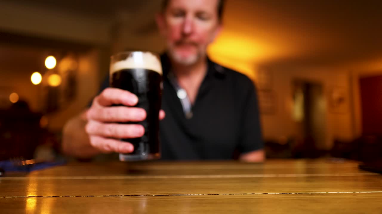 Uomo beve birra stout in un pub
