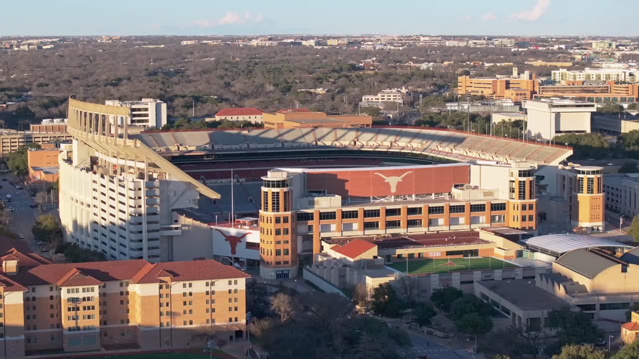 A wide drone shot at sunset gaining elevation and revealing the Longhorns logo on the empty Darrell K Royal Texas Memorial Stadium at the University of Texas (UT) in Austin