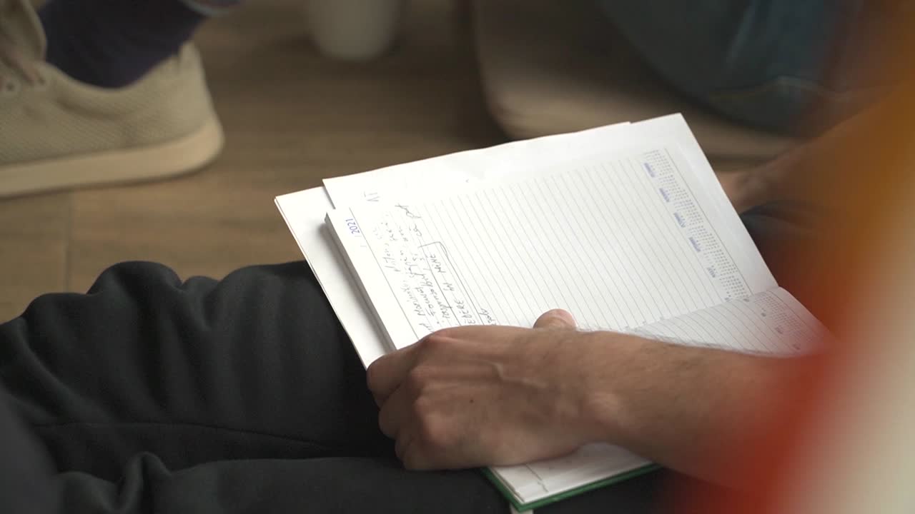 hombre tomando notas en un cuaderno, bebiendo de una lata de café, ambiente relajado, cierre sot