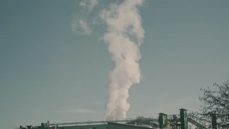 industrial factory with steam going up in the atmosphere, contributing to pollution