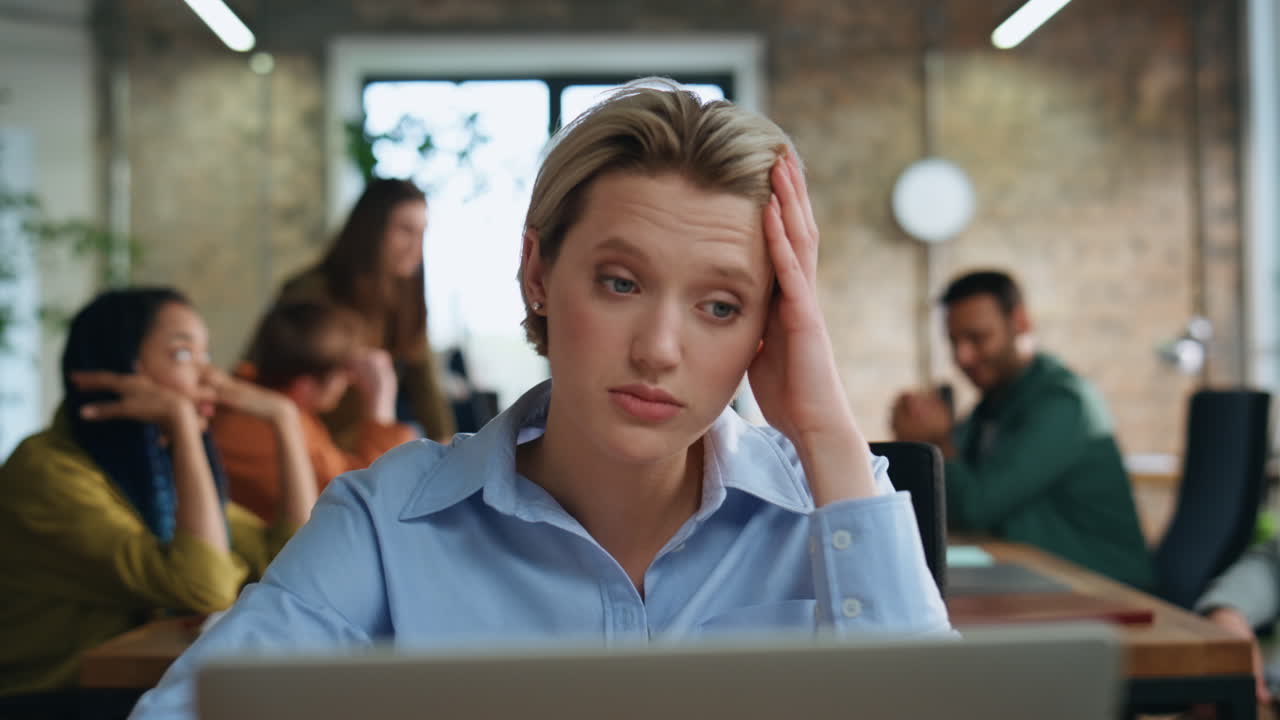 una mujer agotada mirando una computadora portátil leyendo una notificación bancaria en la oficina de cerca.