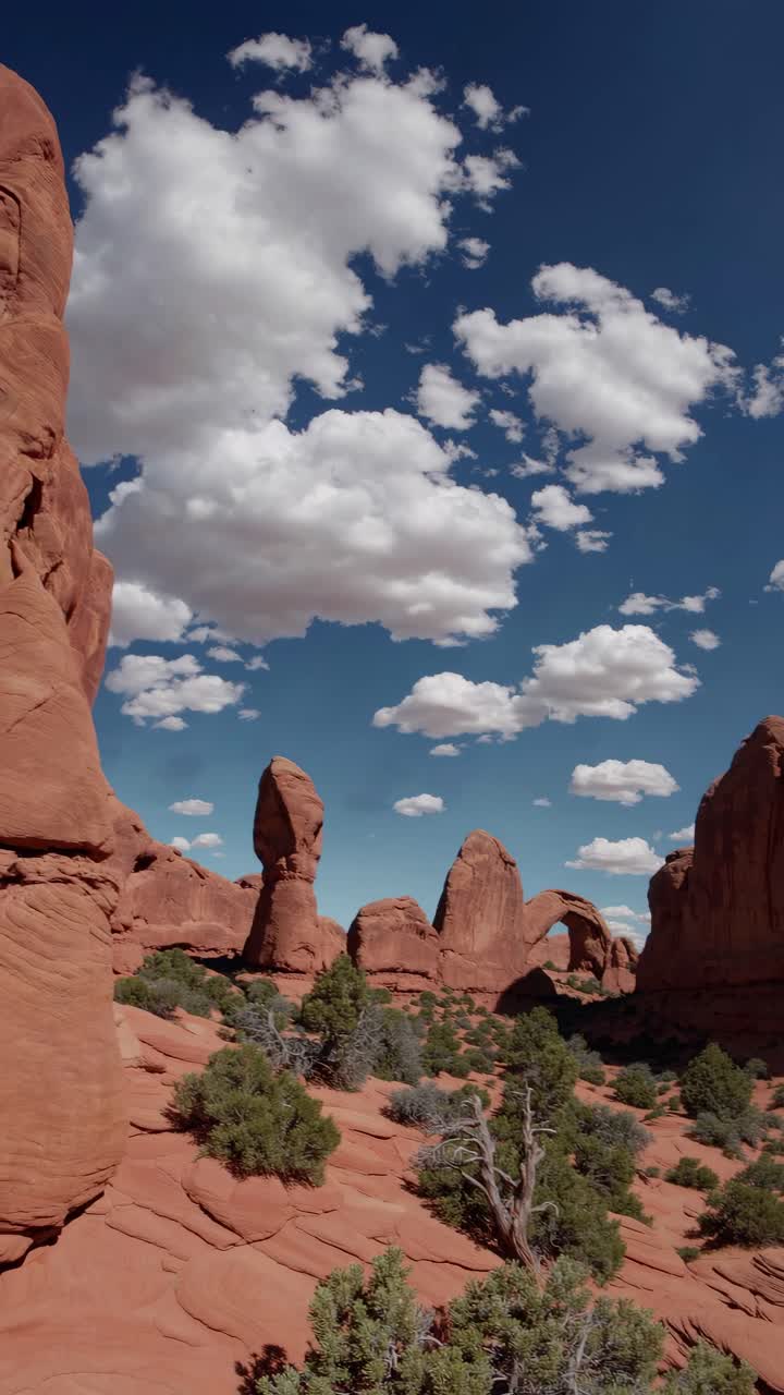 A stunning wide-angle video shot of a desert landscape with red rock formations and a vibrant blue