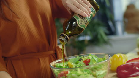 woman hands pouring olive oil to salad. housewife cooking seasonal vegetables.