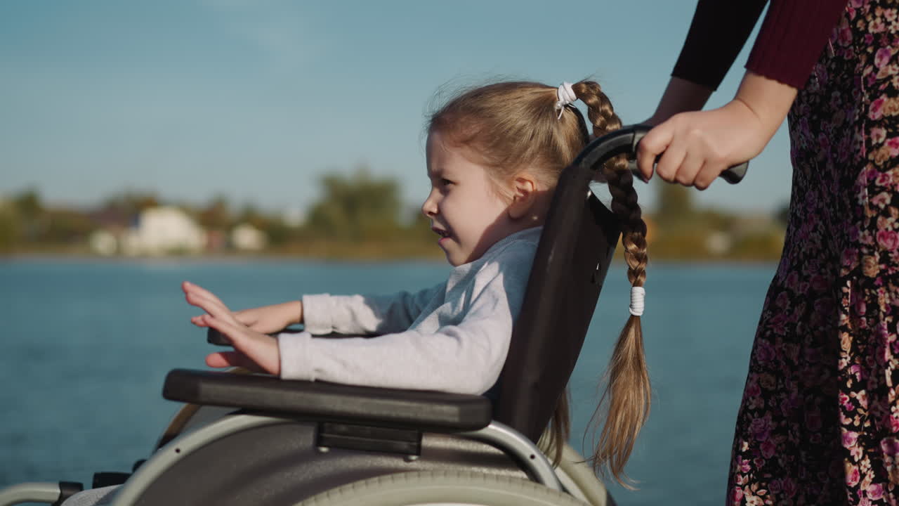 madre y hija con parálisis caminan cerca del estanque