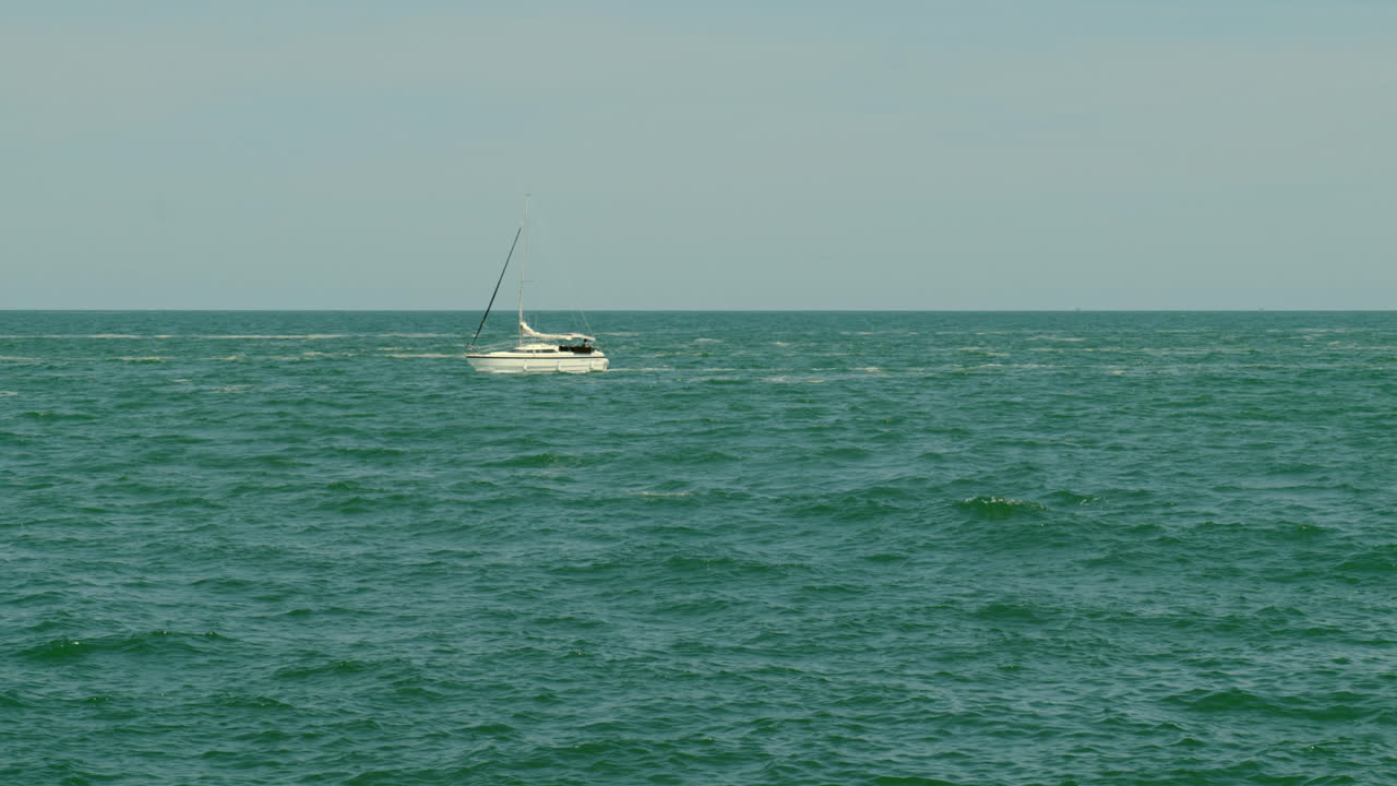 одинокая парусная лодка плавает на открытом море под чистым небом