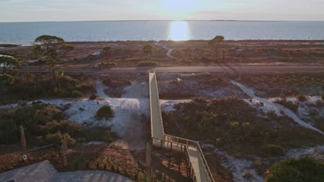 Aerial-flight-showing-a-long-boardwalk,-road-and-path-leading-to-a-Florida-beach