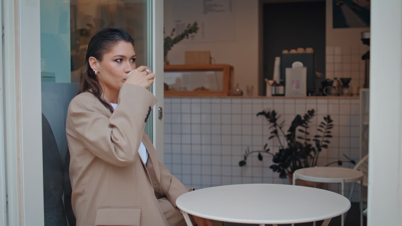 Rolig pige nyder cappuccino på moderne gadecafé, nærbillede. Afslappet forretningskvinde.