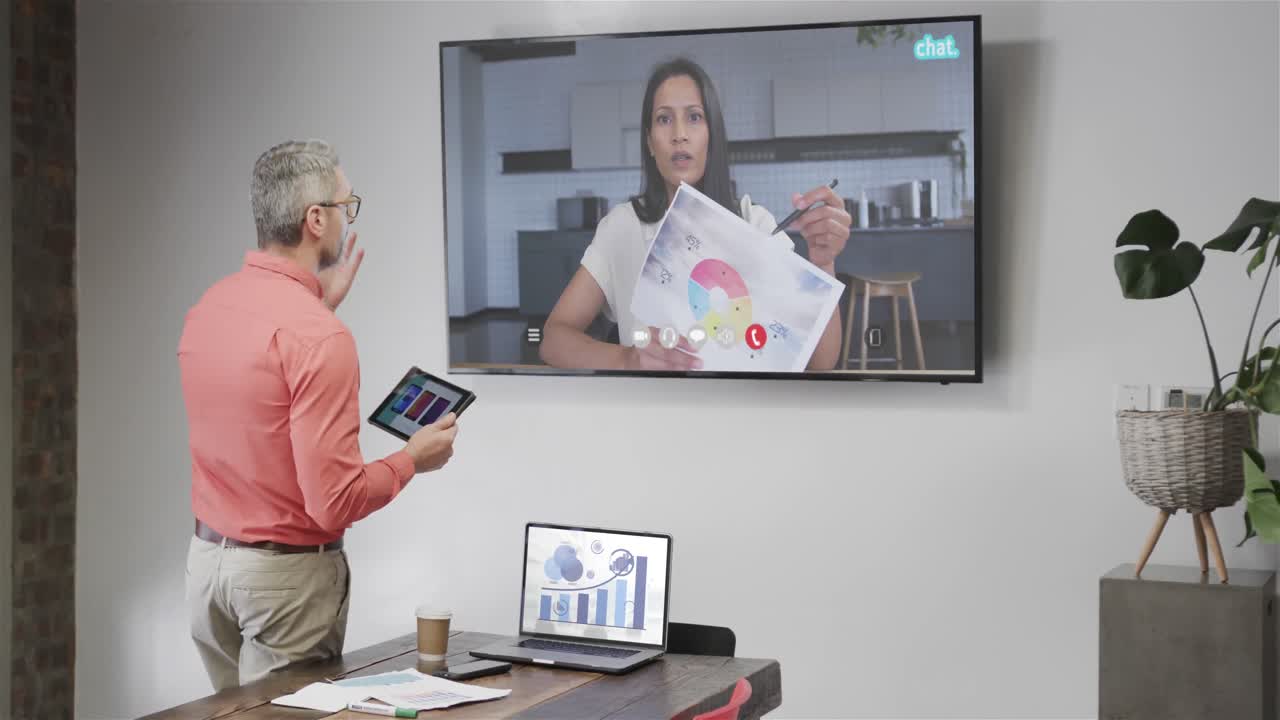 hombre de negocios caucásico en videollamada con una colega caucásica en la pantalla de televisión