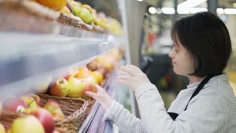 Mujer-Con-Síndrome-De-Down-Reponiendo-Frutas-Frescas-En-Una-Tienda-De-Comestibles,-Vista-Lateral