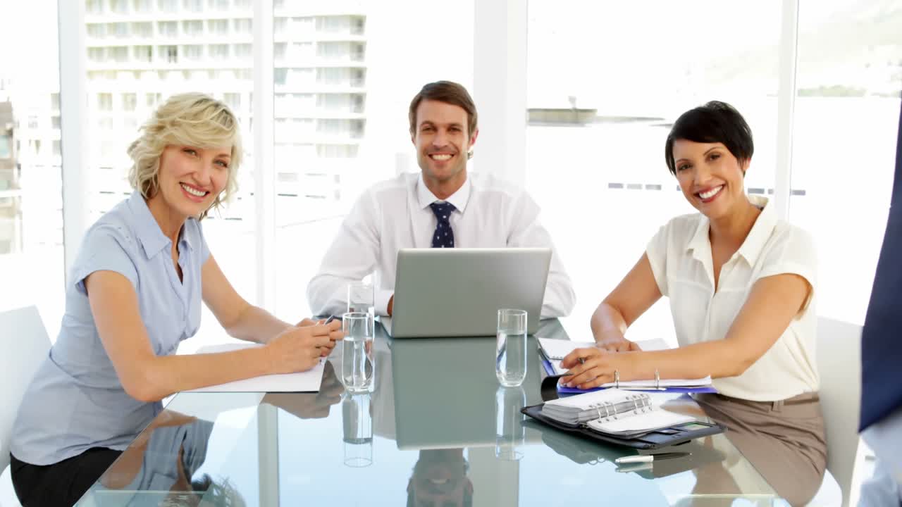 Professionisti che sorridono alla fotocamera durante una riunione.