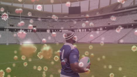 covid-19 cells against male rugby player holding rugby ball on sports field
