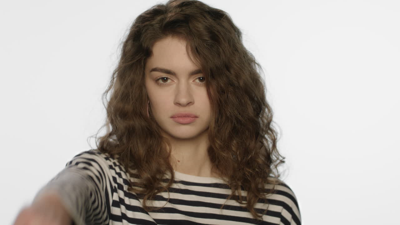 Upset woman showing thumbs down in studio. Unhappy girl showing dislike gesture
