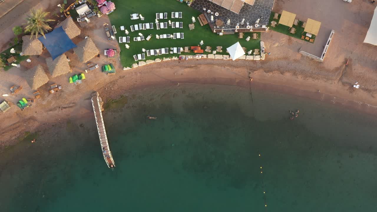 홍해, 에일랏, 이스라엘 공중에서 수영하는 사람들을 위한 수중 산호와 부두가 있는 사막에 텐트 잔디와 그늘이 있는 흠 잡을 데 없는 깨끗한 해변